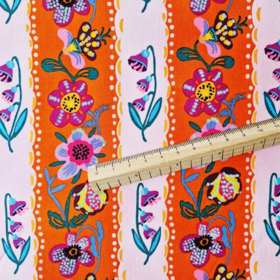 alternance de rayures mauves et oranges pour ce tissu en coton imprimé Nathalie Lété des fleurs mauves jaunes violettes animent ces rayures