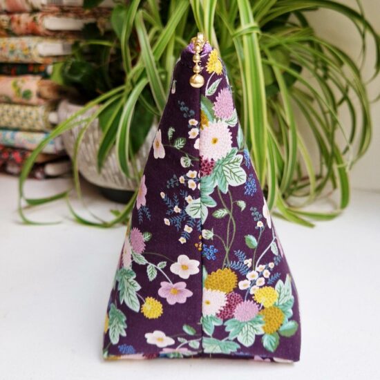 Joli volume pour cette trousse en tissu rifle paper co molletonnée imprimé Dahlia avec ces fleurs ocre jaune écru mauve bordeaux sur fond prune