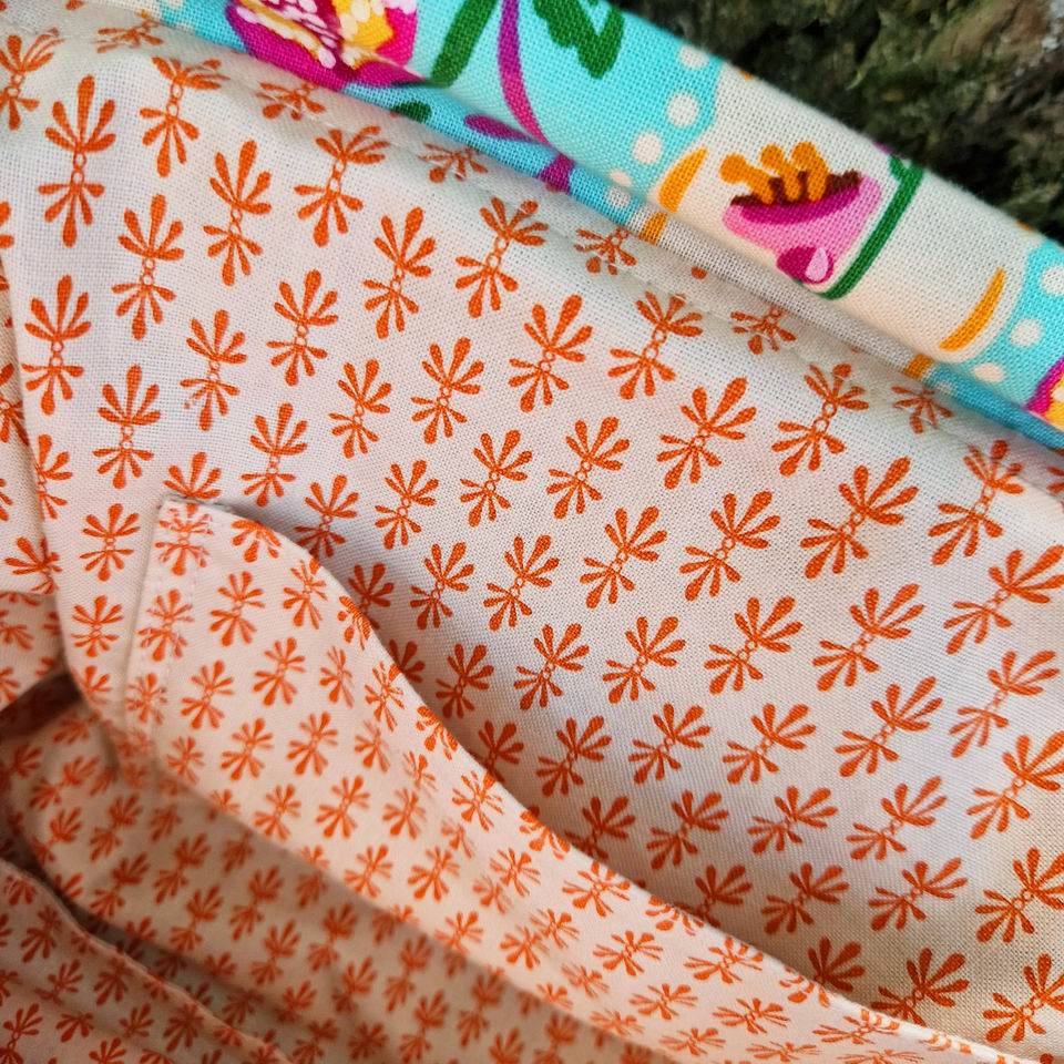 Joli et pratique poche latérale pour cette trousse à projets tricot ou trousse de toilette tissu fleurs et rayures Nathalie Lété, la doublure est en coton Rifle Paper Co imprimé mini motifs graphiques géométriques orange sur fond écru