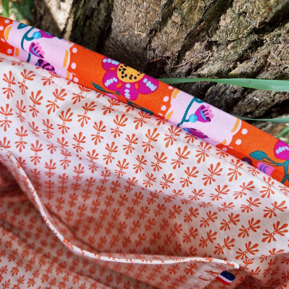 Joli et pratique poche latérale pour cette trousse à projets tricot tissu fleurs et rayures Nathalie Lété, la doublure est en coton Rifle Paper Co imprimé mini motifs graphiques géométriques orange sur fond écru