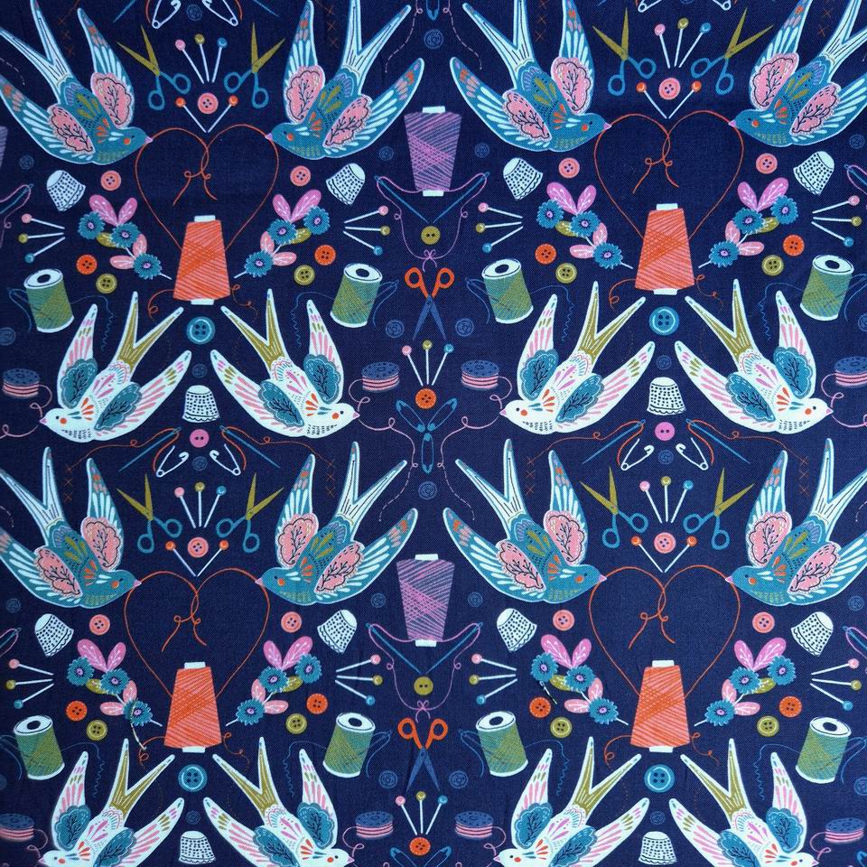 Tissu imprimé thème de la couture avec des hirondelles blanches sur fond bleu marine bobines de fil orange et vertes