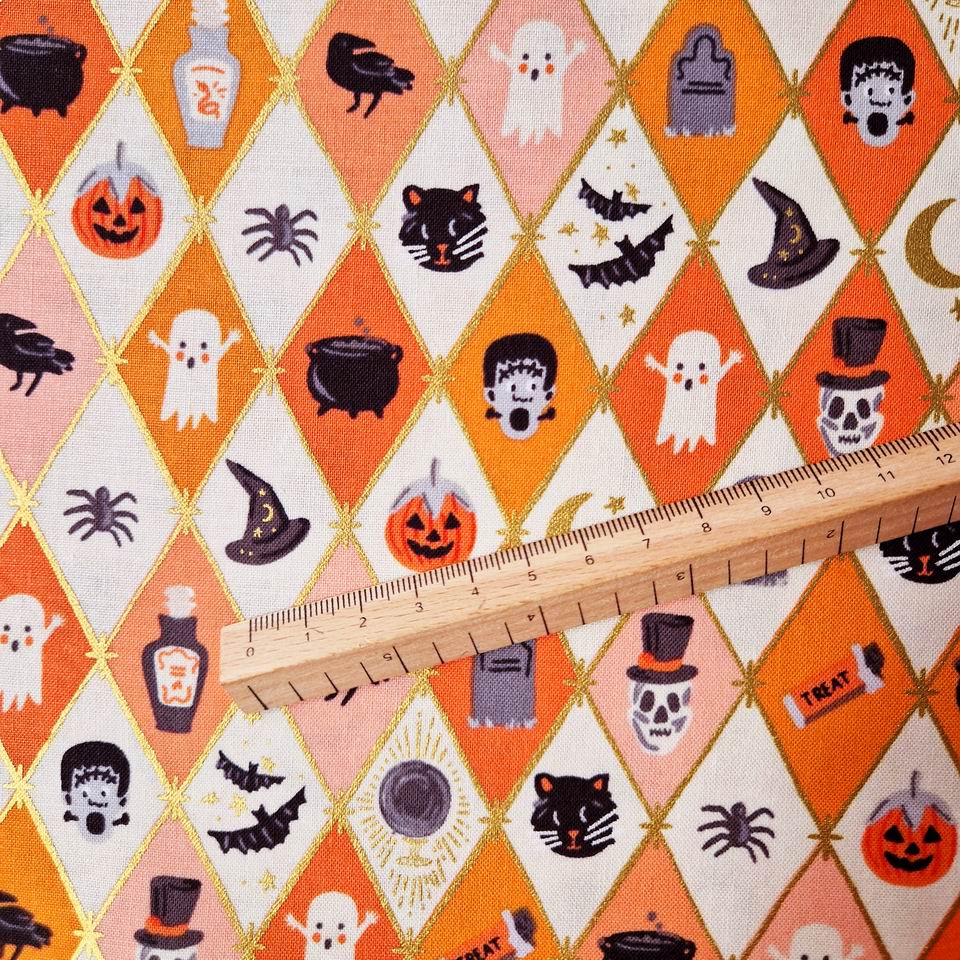 Tissu coton imprimé Rifle paper Co Halloween motif géométrique, resille métallisée or, imprimé graphique, alternance de losanges blanc et orange, au centre un dessin araignée, chauve souris noire, fantome blanc, citrouille orange, fiole de poison, tête de squelette