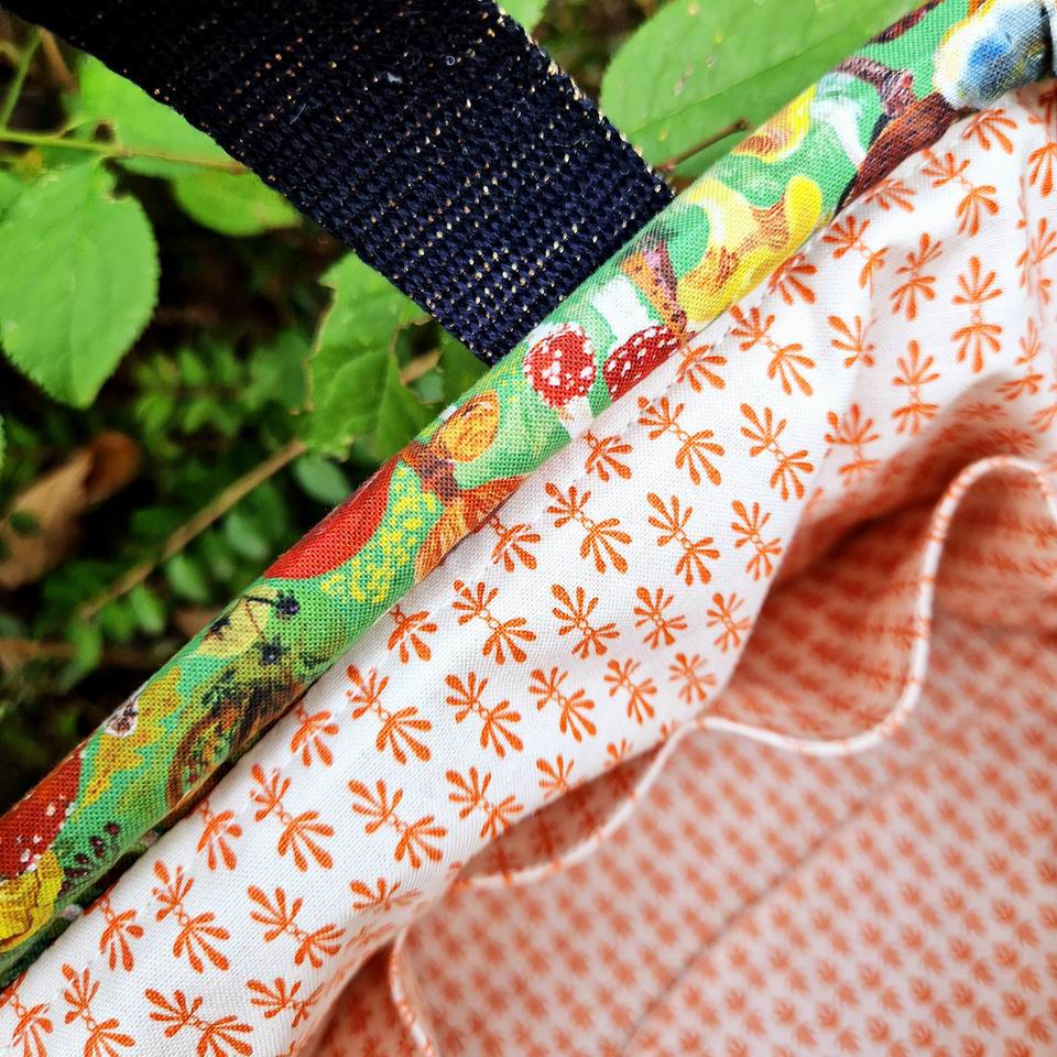 Multi poches pour ce sac à projets tricot clap clap en tissu imprimé champignons Nathalie Lété, la doublure est en coton Rifle Paper Co imprimé mini motifs graphiques géométriques orange sur fond écru